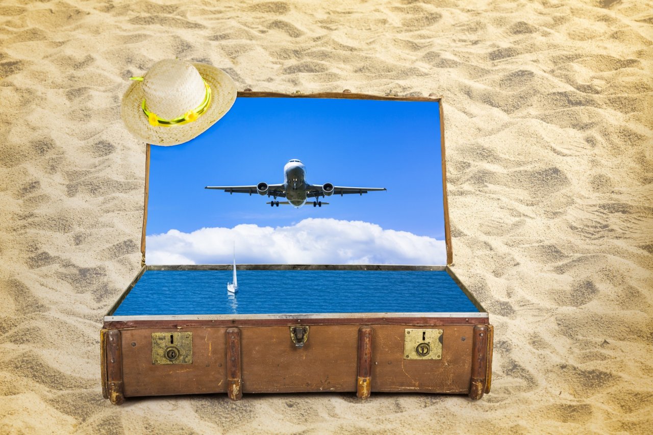 Koffer mit Strohhut und Urlaubssymbolik