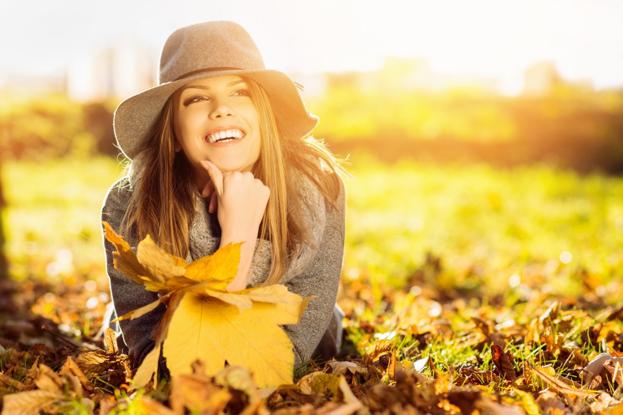Happy young woman in park on sunny autumn day