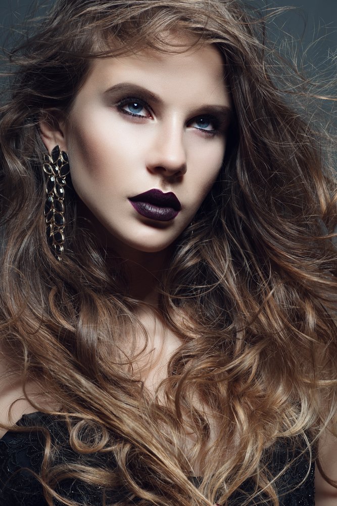 Portrait of a beautiful girl with long curly hair in the studio in the Gothic style