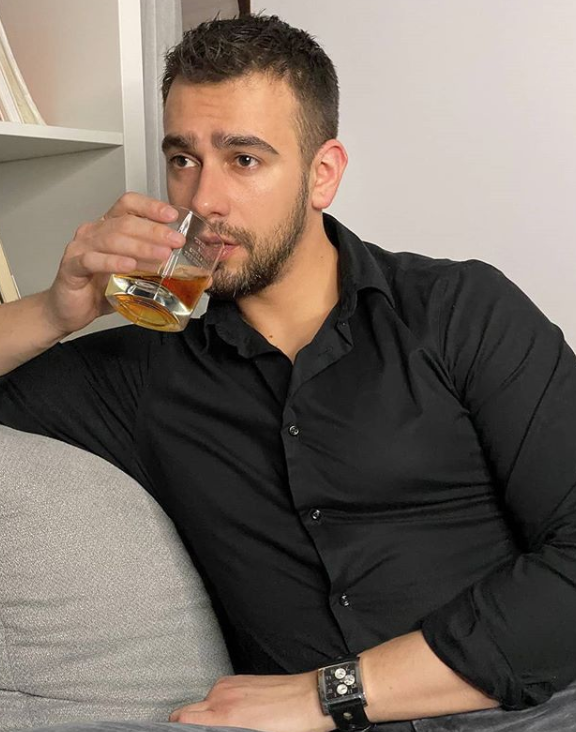 Łukasz Kuchta pije napój w czarnej koszuli