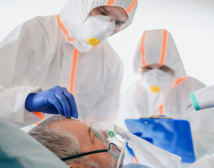 lekarze w kombinezonach i maskach pochylają się nad chorym