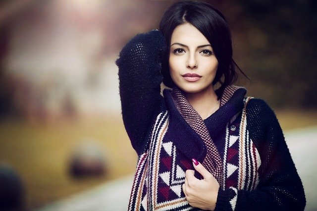brunetka z kolczykiem w nosie i spiętych włosach łapie się ręką za tył głowy