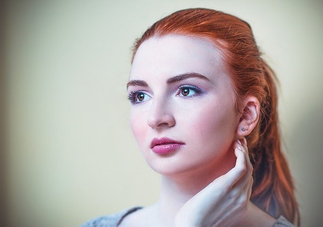 rudowłosa dziewczyna o jasnej skórze patrzy w dal