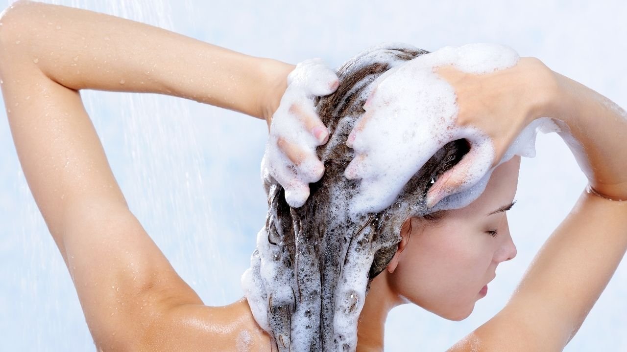 zdjęcie kobiety od tyłu, która myje głowę i spogląda w bok