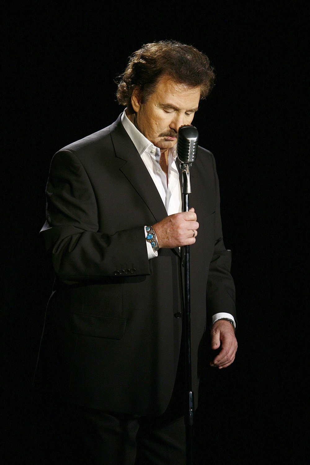 Zamyślony Krzysztof Krawczyk trzyma mikrofon 