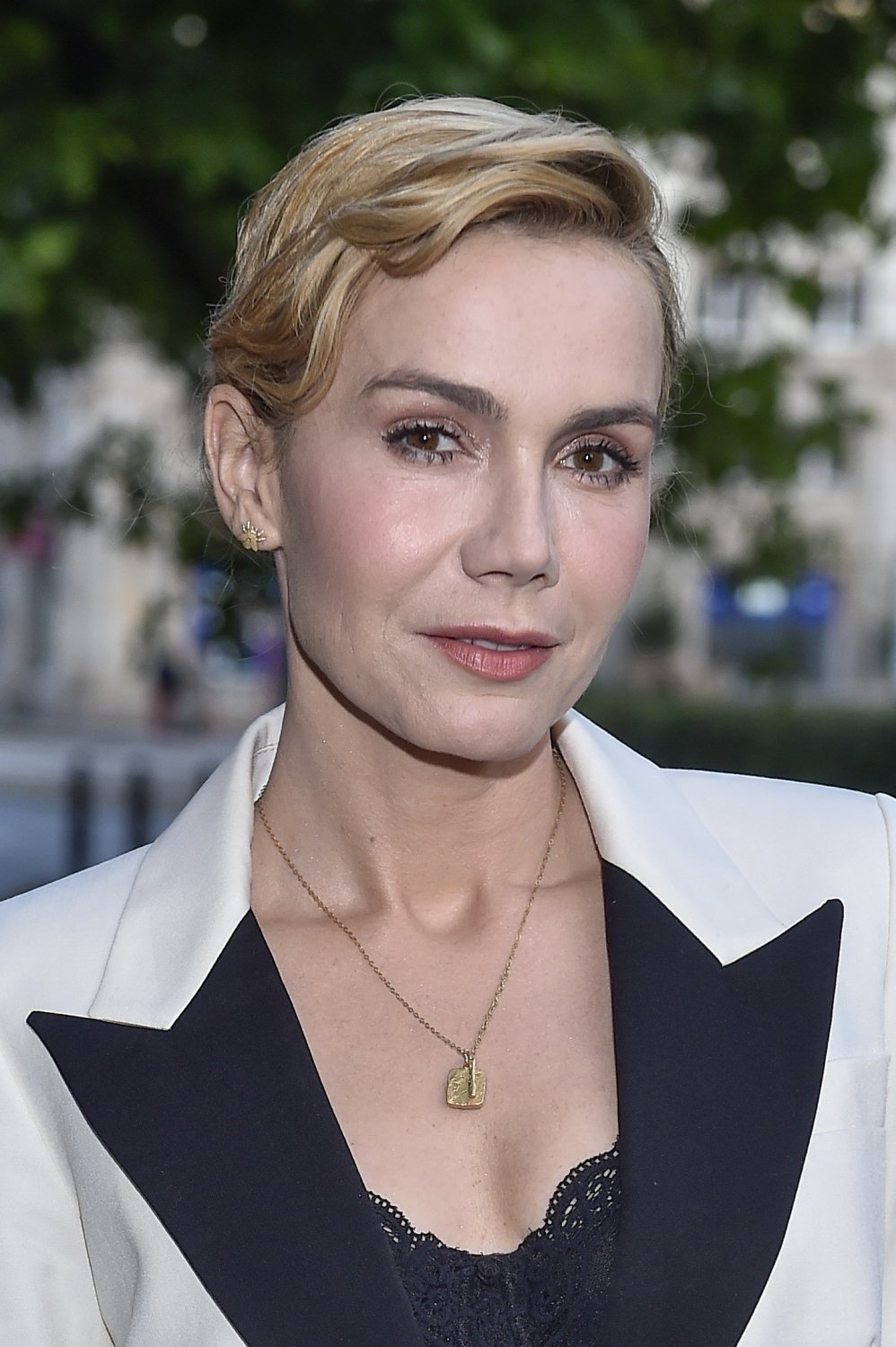 Olga Bołądź w spiętych blond włosach i białej marynarce
