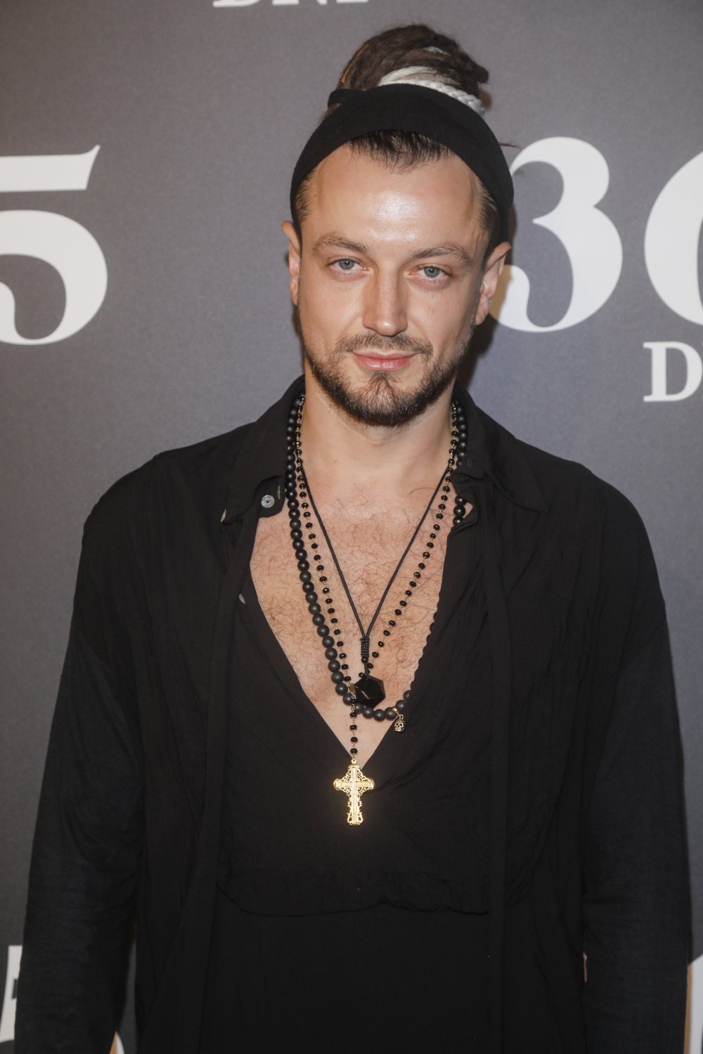 Aleksander Milwiw-Baron w spiętych włosach i rozpiętej koszuli 