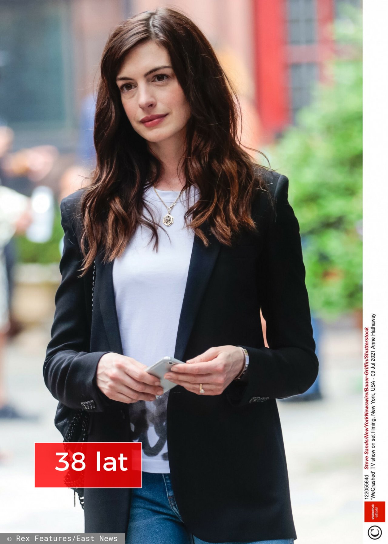 Anna Hathaway w rozpuszczonych włosach, białej koszulce, marynarce i jeansach