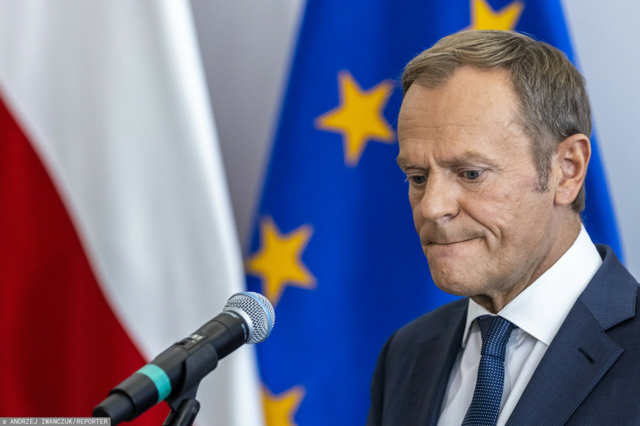 Donald Tusk na tle polskiej i unijnej flagi
