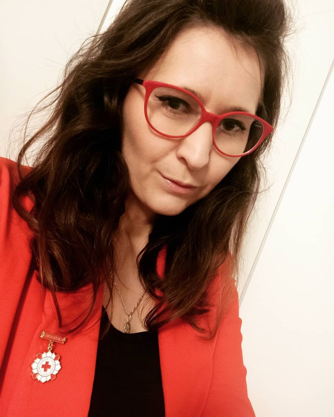 Agata Rusak w czerwonej marynarce, czerwonych okularach i rozpuszczonych, ciemnych włosach