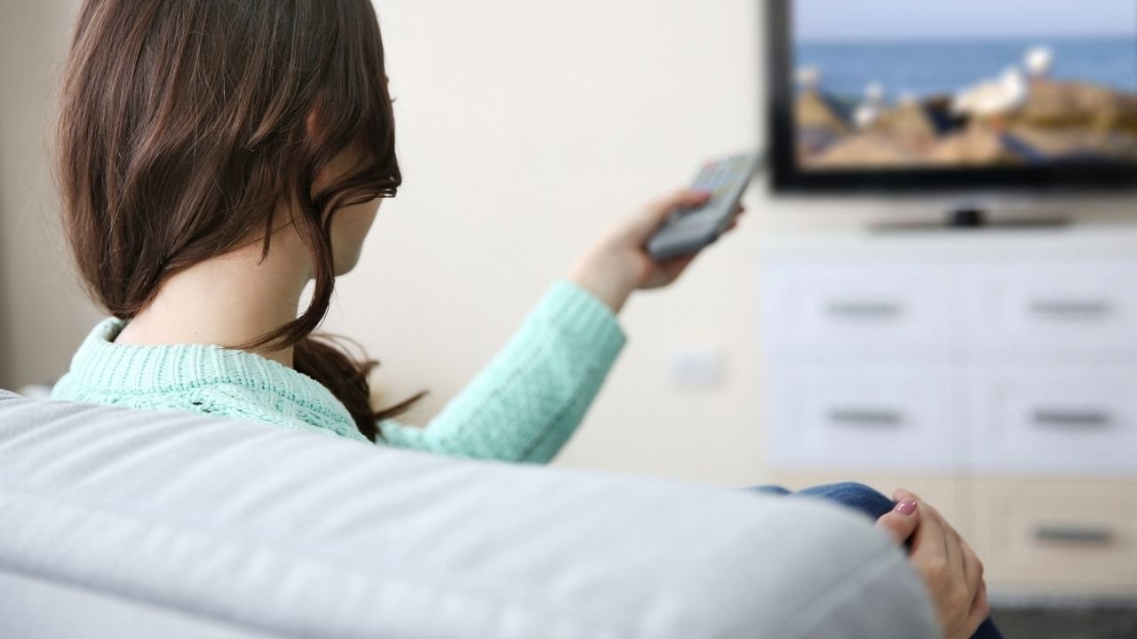 kobieta siedzi na kanapie i ogląda telewizję