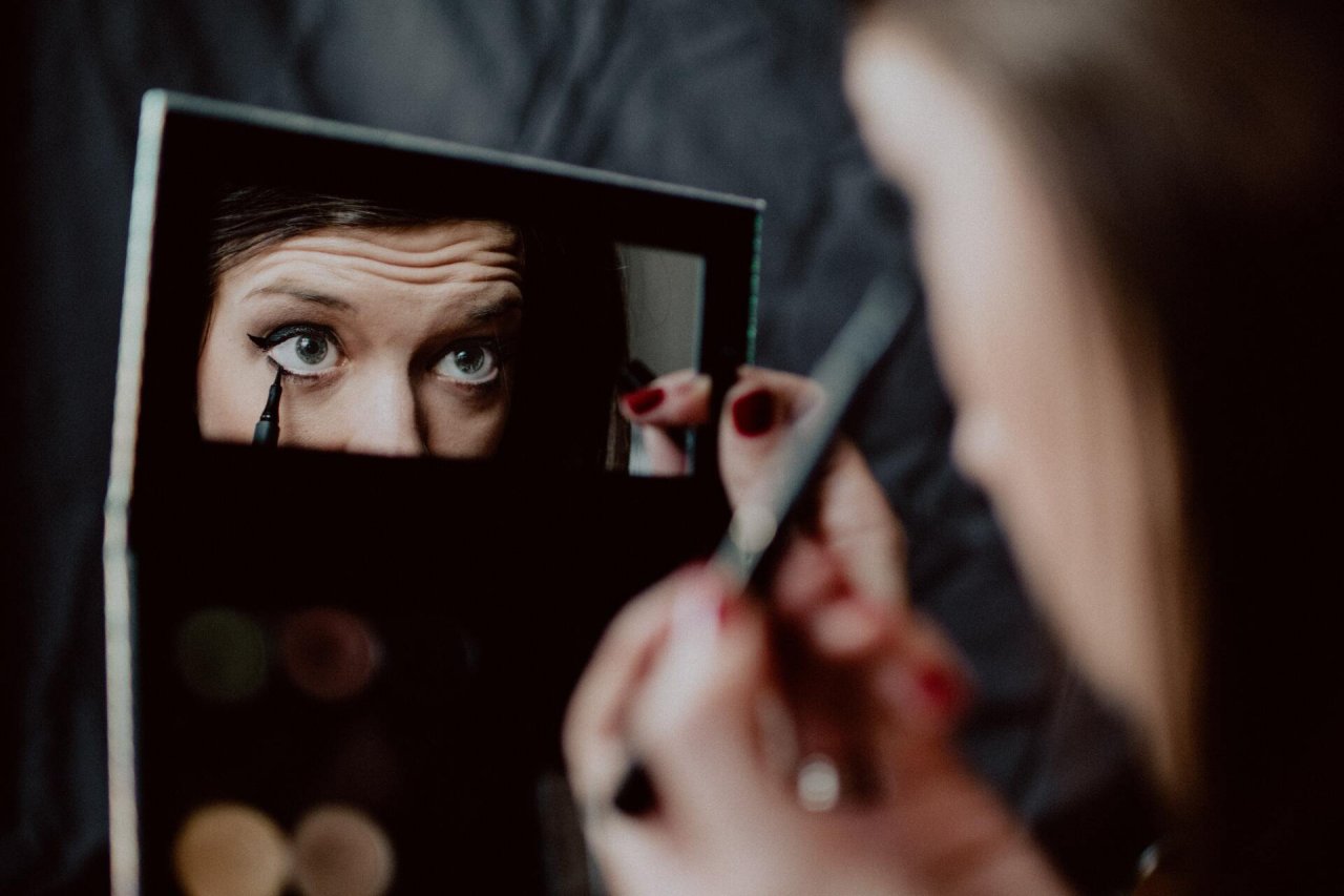 Kobieta przegląda się w lustrze podczas malowania oczu