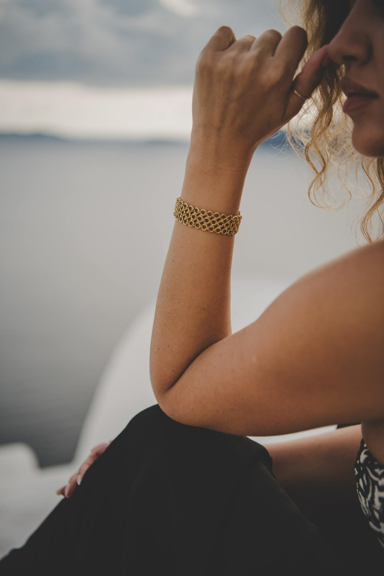 Złota bransoletka na ręce kobiety w lokach