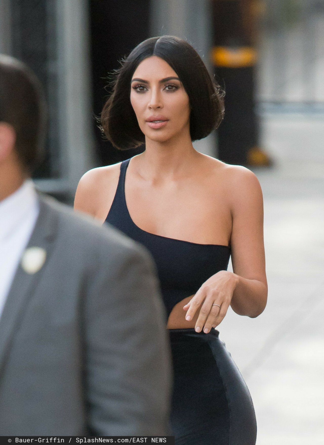Kim Kardashian w czarnej bluzce z asymetrycznym dekoltem