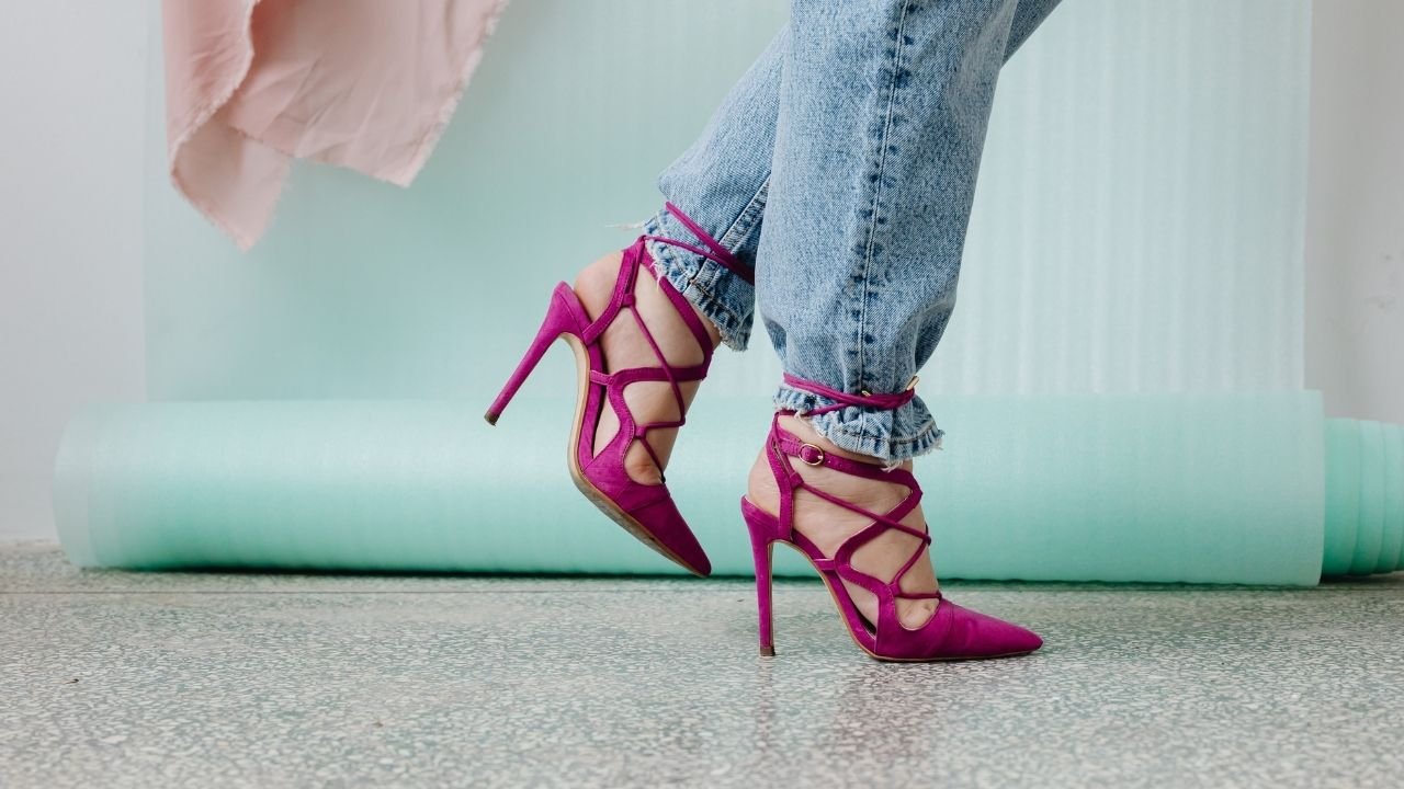 Kobiece nogi w jeans spodniach oraz różowych fuksja szpilkach