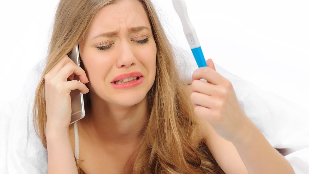 rozżalona kobieta trzyma test ciążowy i rozmawia przez telefon
