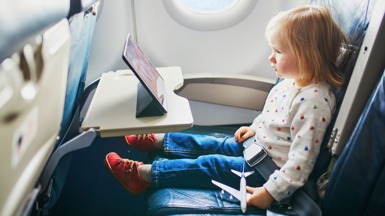 mała dziewczynka siedzi przy oknie samolotu