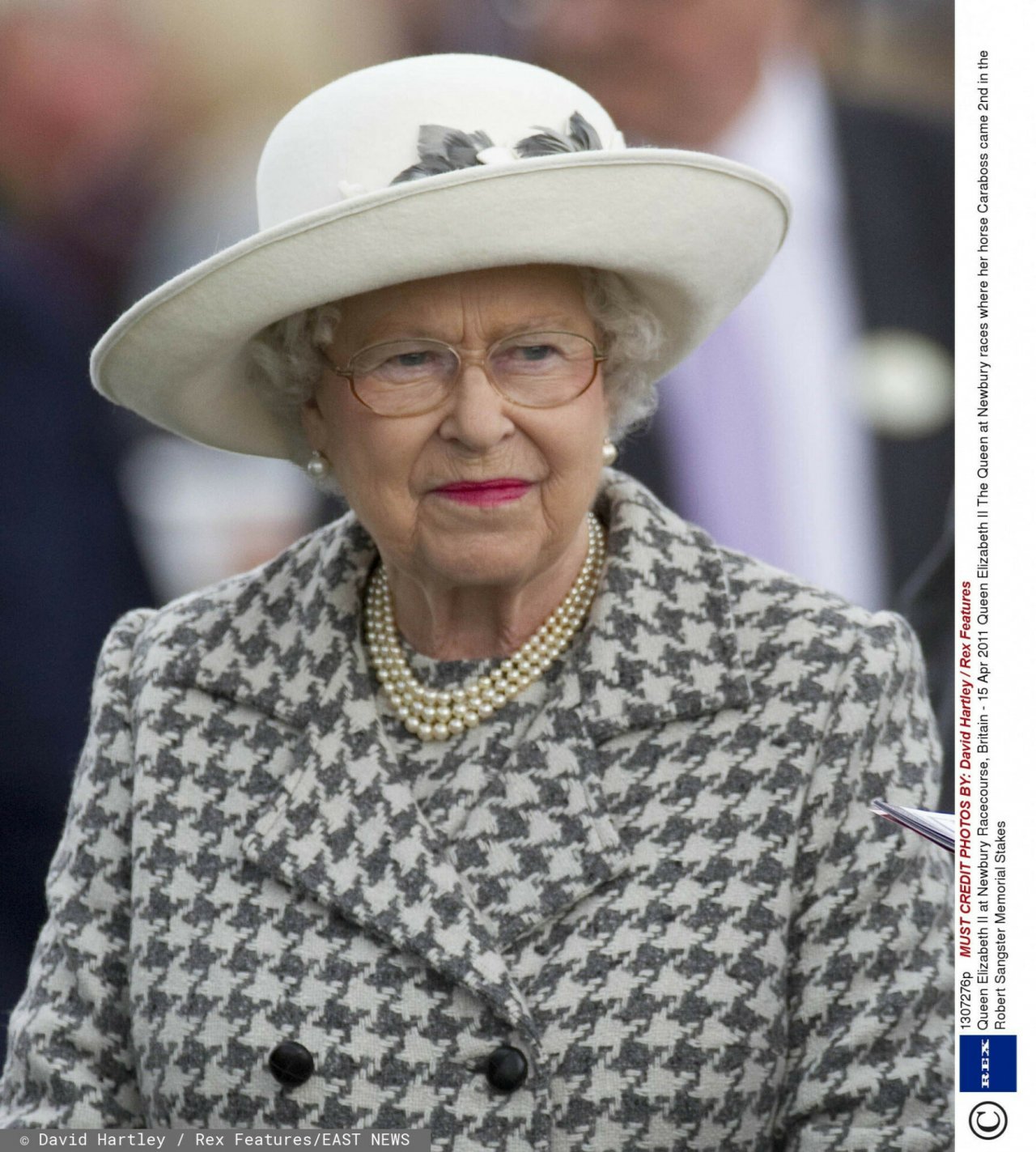 Elżbieta II w płaszczu w kratkę i jasnym kapeluszu 