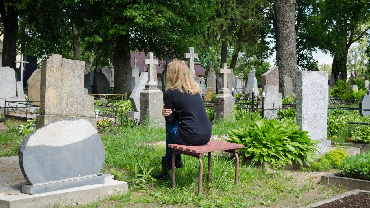 Kobiety siedzi na ławce przy grobie