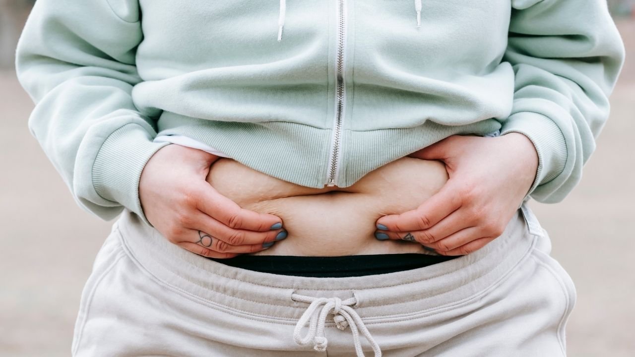Kobieta trzyma się za tłuszcz na brzuchu
