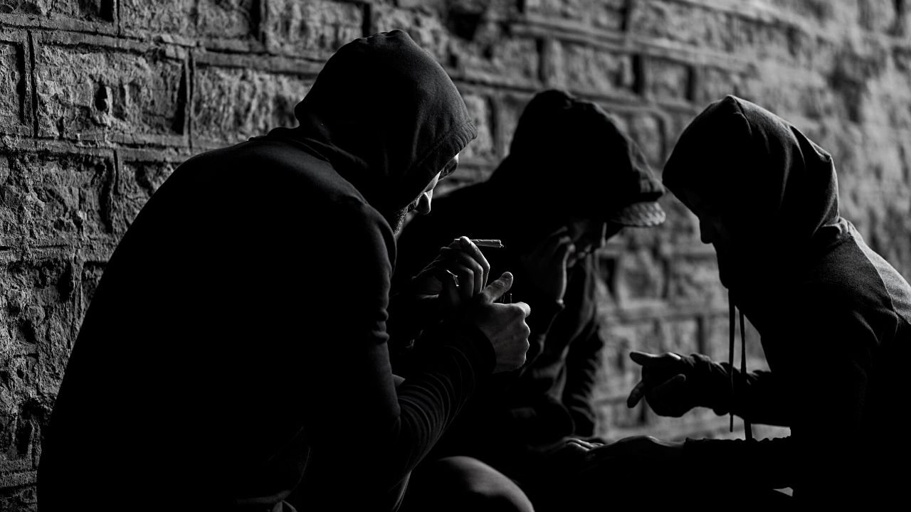 Młodzież w kapturach siedzi pod ścianą