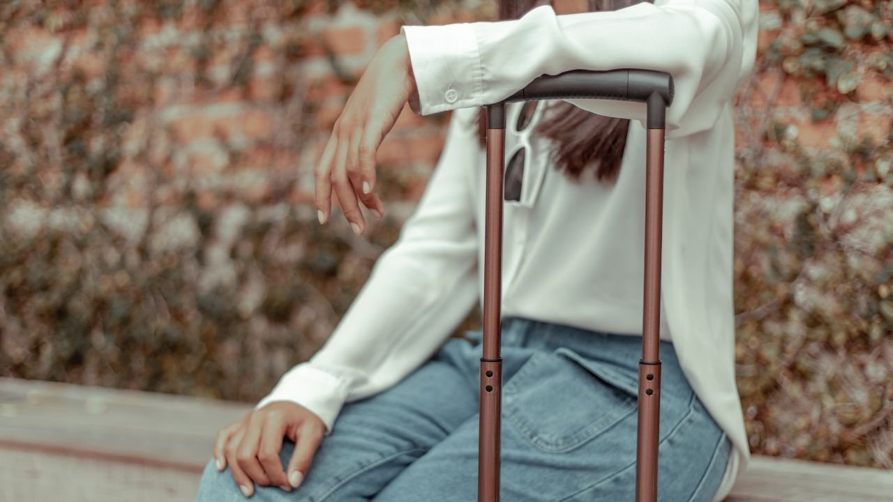 Kobieta opiera się o rączkę walizki