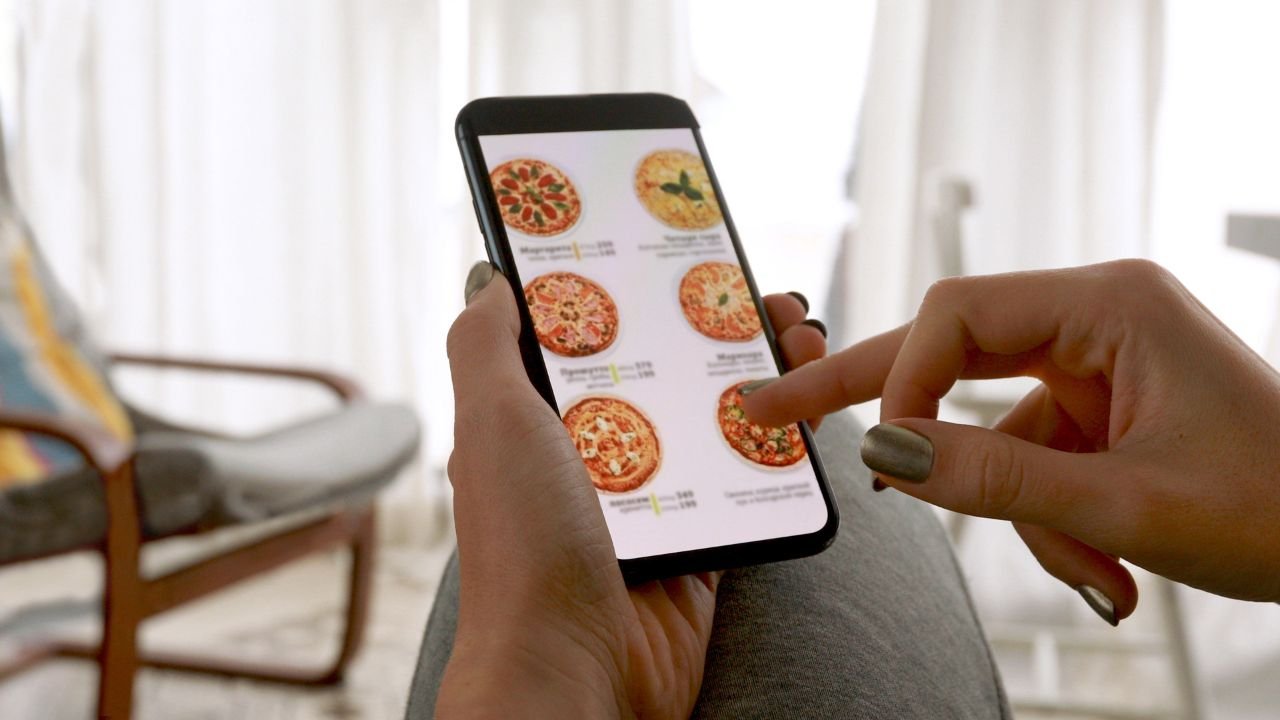 kobieta szuka pizzy w telefonie