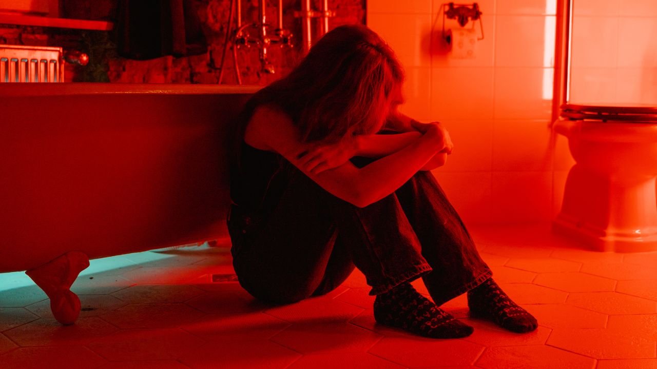 kobieta siedzi na podłodze w pomieszczeniu z czerwonym światłem 