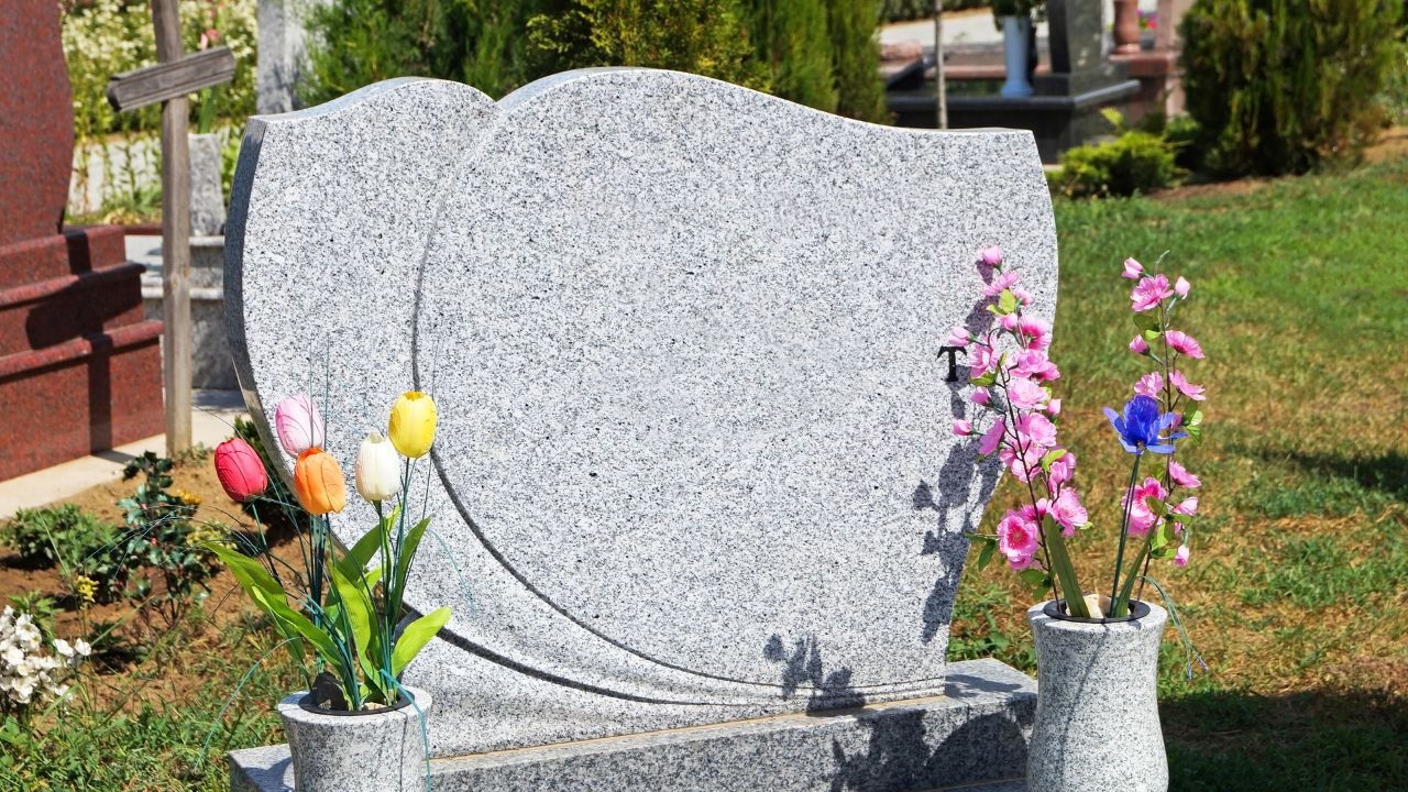 nagrobek z szarego granitu ozdobiony kolorowymi kwiatami