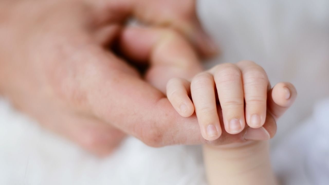 dloń niemowlaka trzyma palec osoby dorosłej