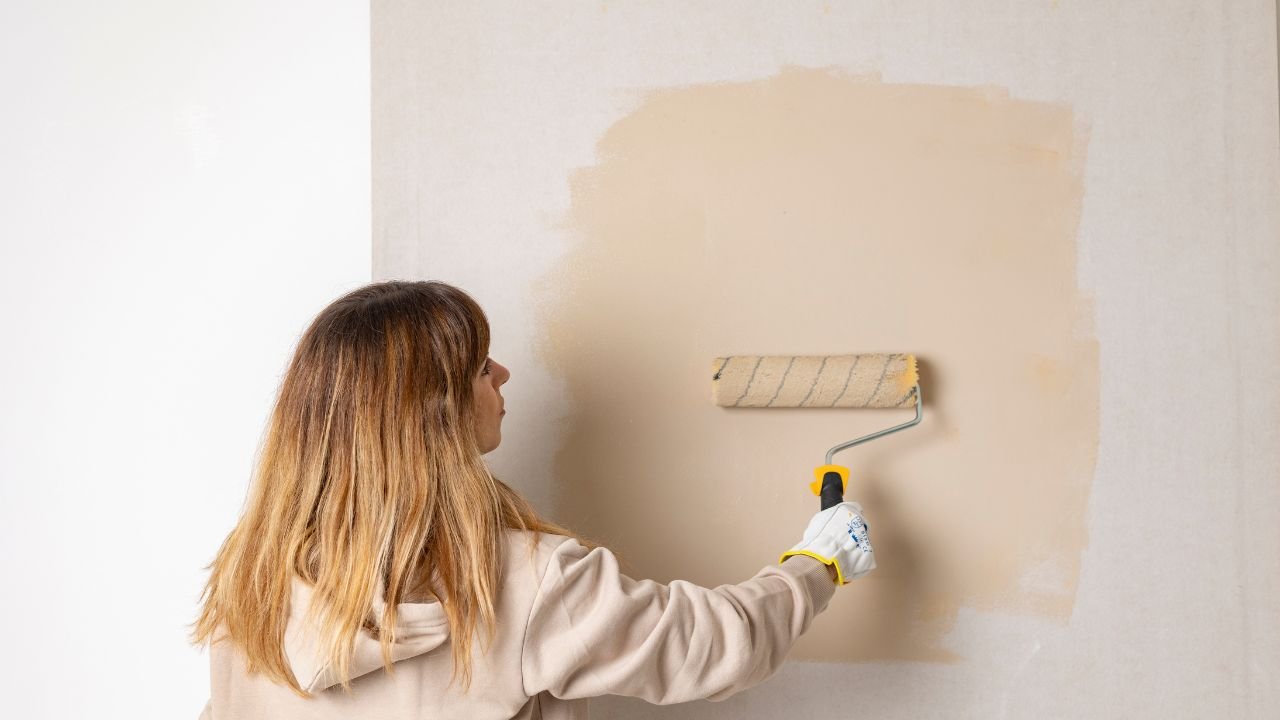 kobieta maluje ścianę na beżowo