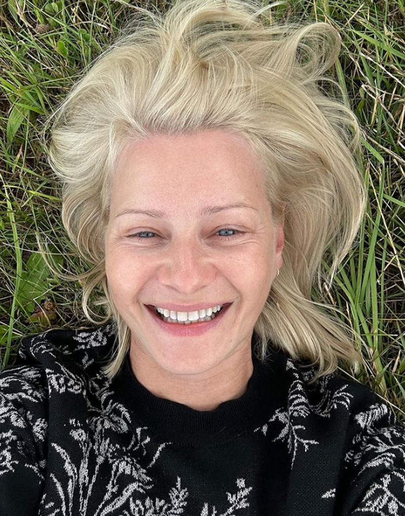 Małgorzata Kożuchowska leży na trawie bez makijażu i usmiecha się szeroko
