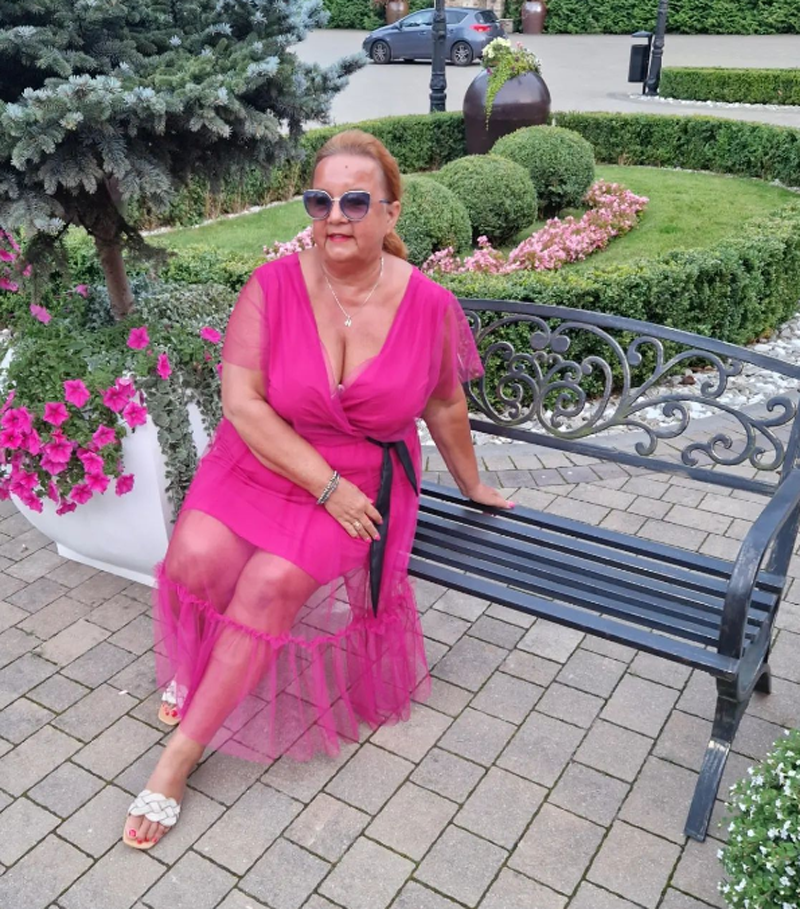 Iza Zeiske w różowej sukience siedzi na ławce