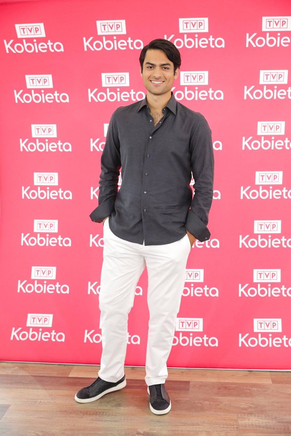 Matteo Bocelli w czarnej koszuli i białych spodniach uśmiecha się szeroko 