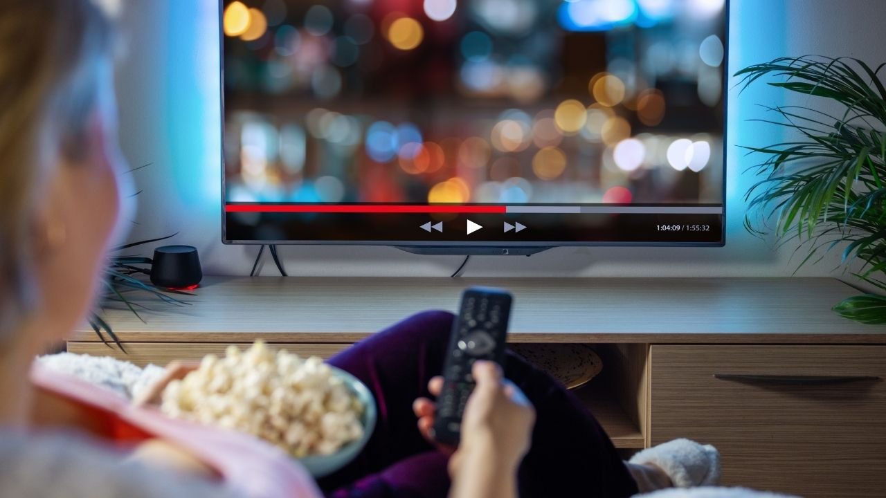 kobieta siedzi na kanapie i ogląda telewizor