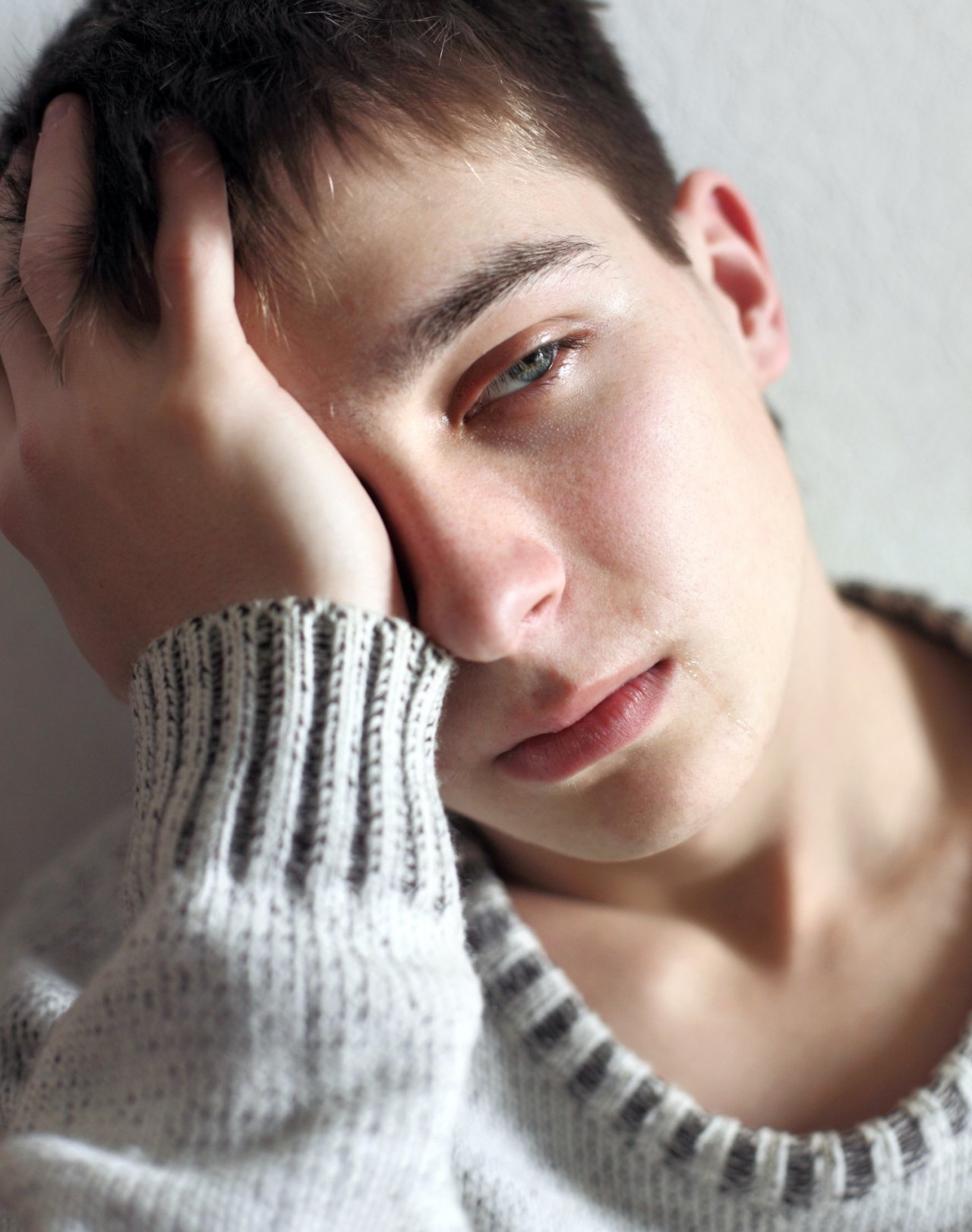 Płaczący nastolatek w szarym swetrze