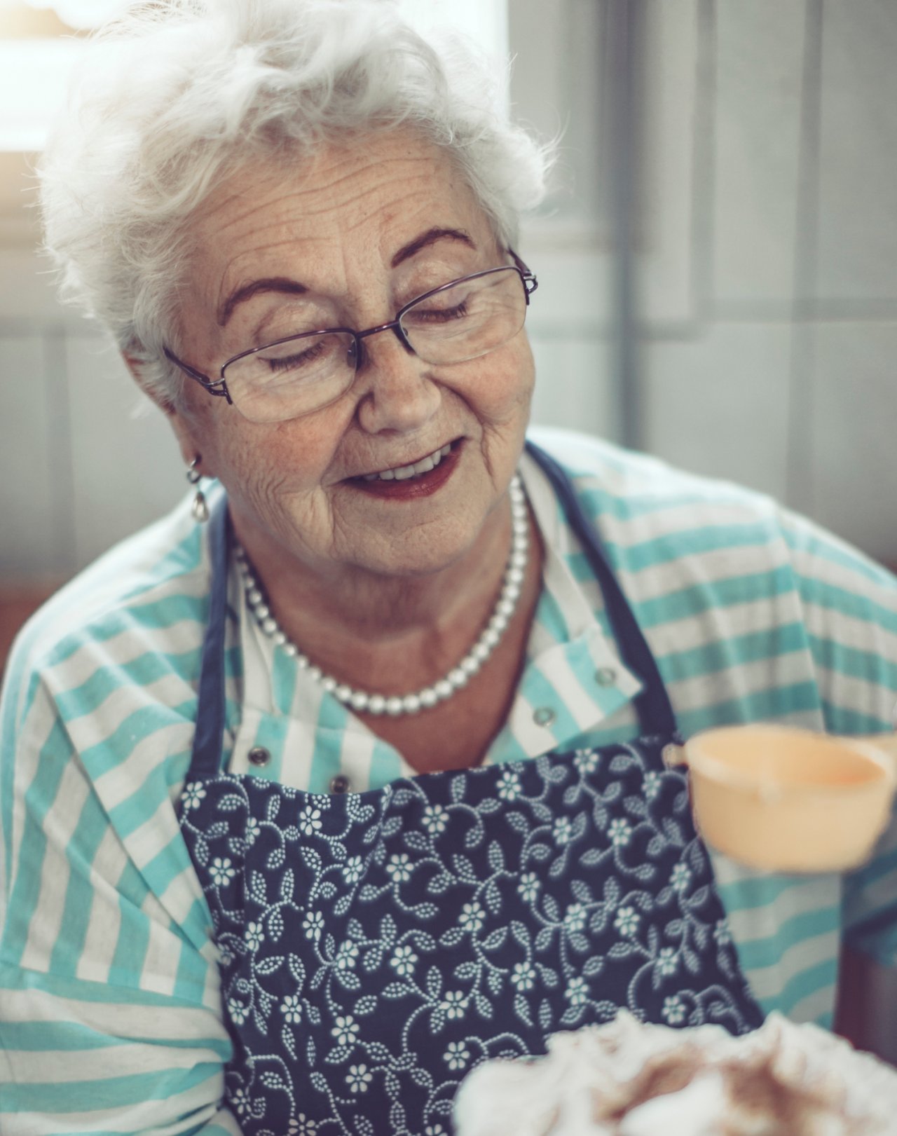 Babcia w fartuchu posypująca ciasto cukrem pudrem