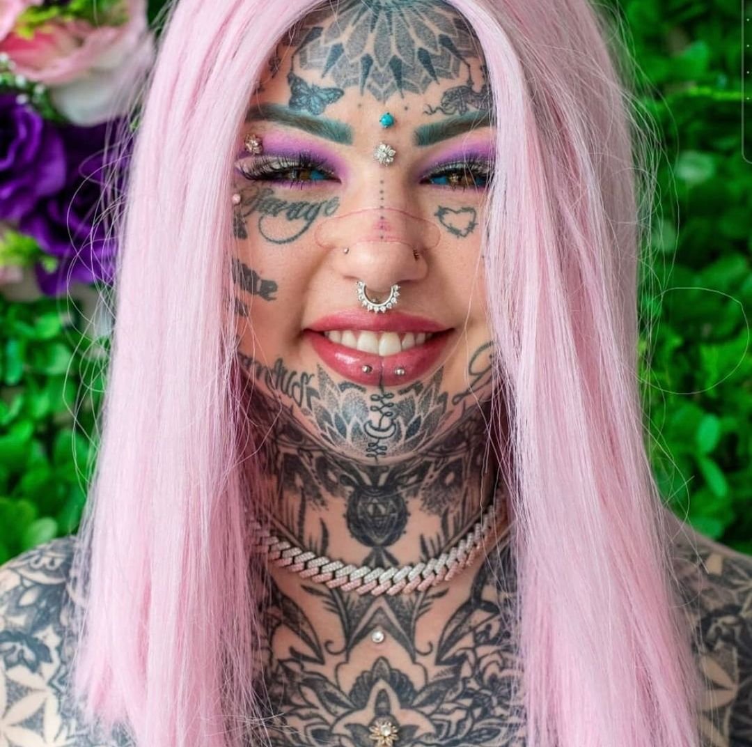 Amber Luke w różowych włosach i tatuażach na twarzy i szyi