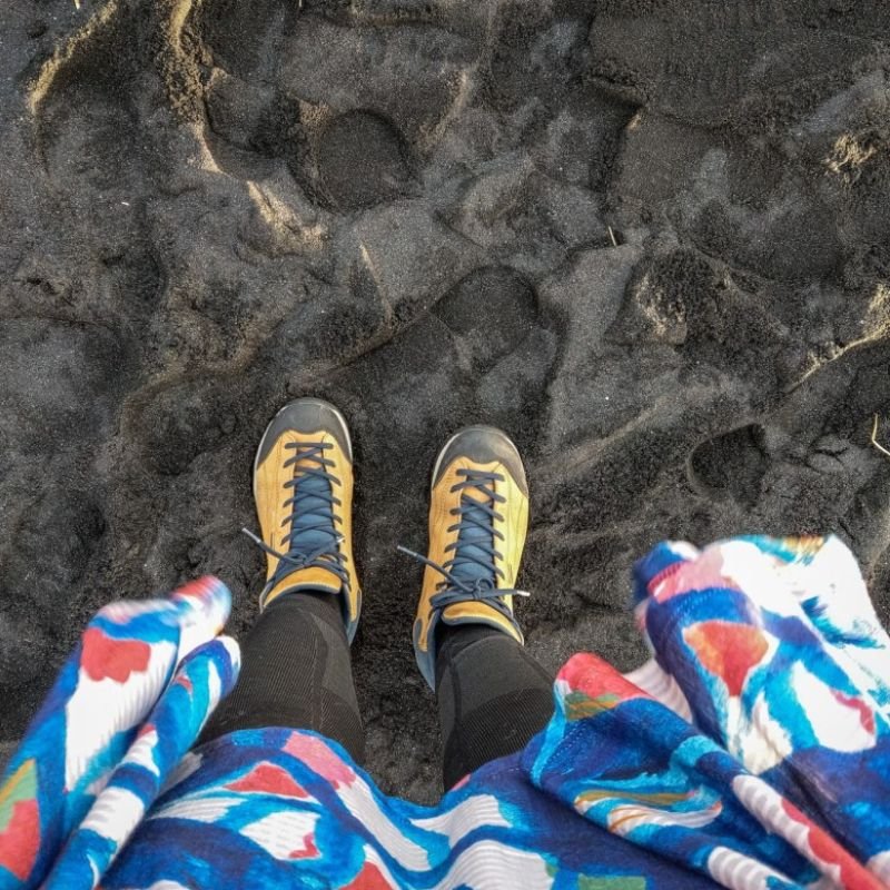 W ubraniach z merino gorpcore oraz ciepłych sznurowanych butach damskie nogi na zimowej plaży widok z góry