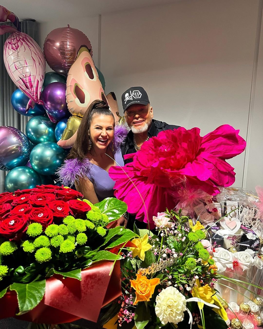 Krzysztof Rutkowski z żoną na tle kwiatów i balonów