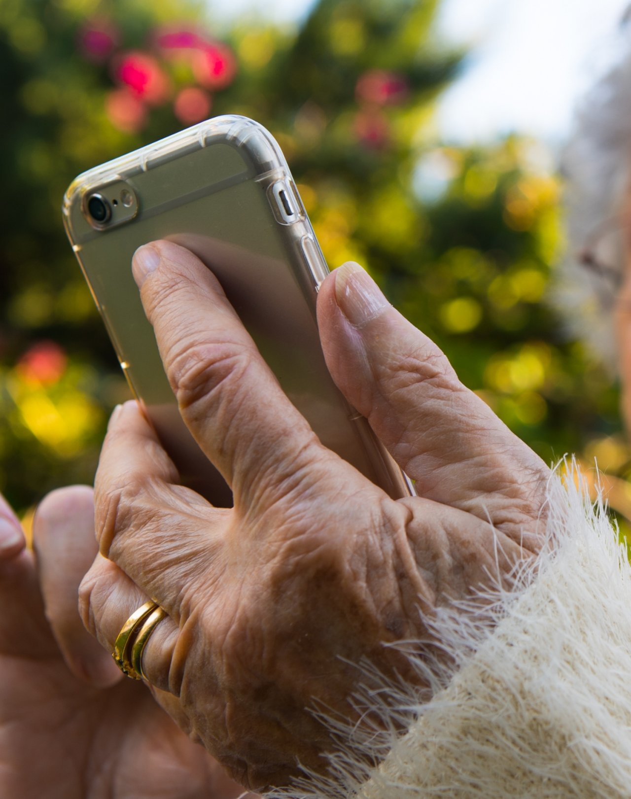 Starsza kobieta trzymająca w dłoni telefon na tle światełek choinkowych