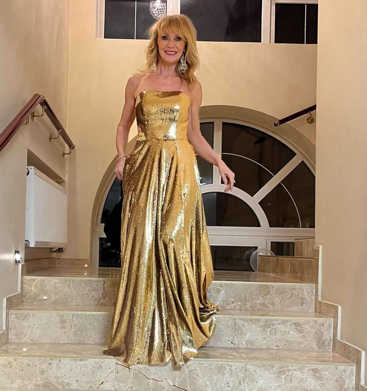 Beata Ścibakówna w złotej sukni idzie po schodach