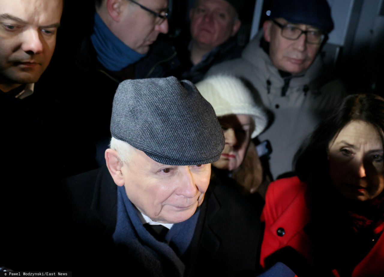 Jarosław Kaczyński w czapce przed aresztem w otoczeniu kolegów