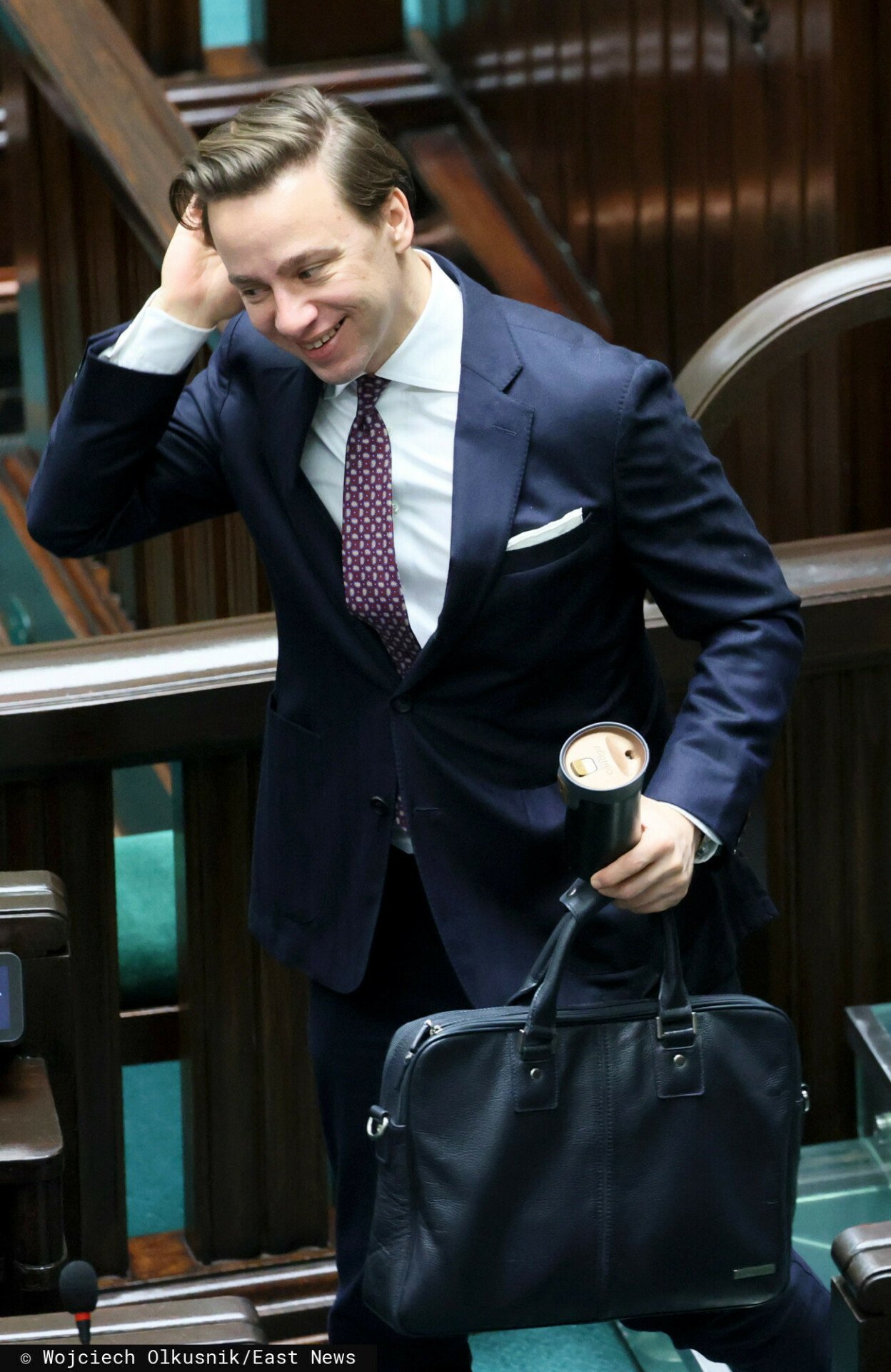 Krzysztof Bosak uśmiechnięty w grantowym garniturze w Sejmie