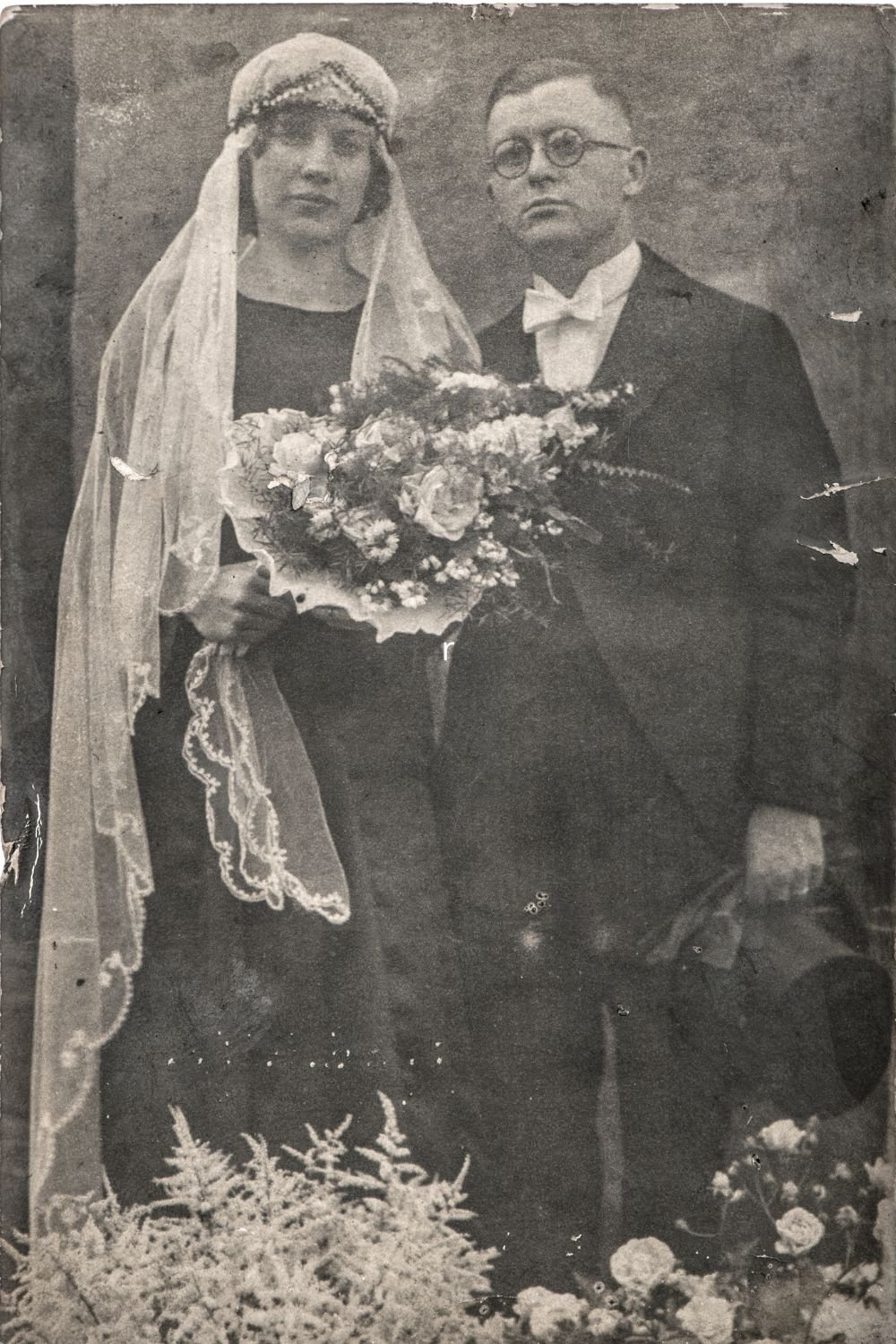 stare zdjęcie ślubne, kobieta z białym welonem i bkietem ślubnym, obok mężczyzna w garniturze i w okularach