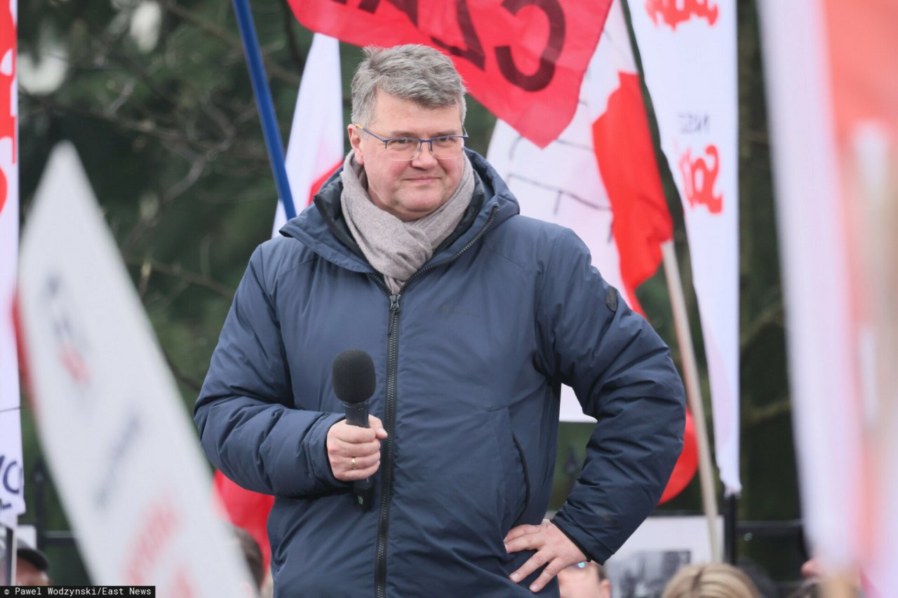 Maciej Wąsik uśmiechnięty w granatowej kurtce