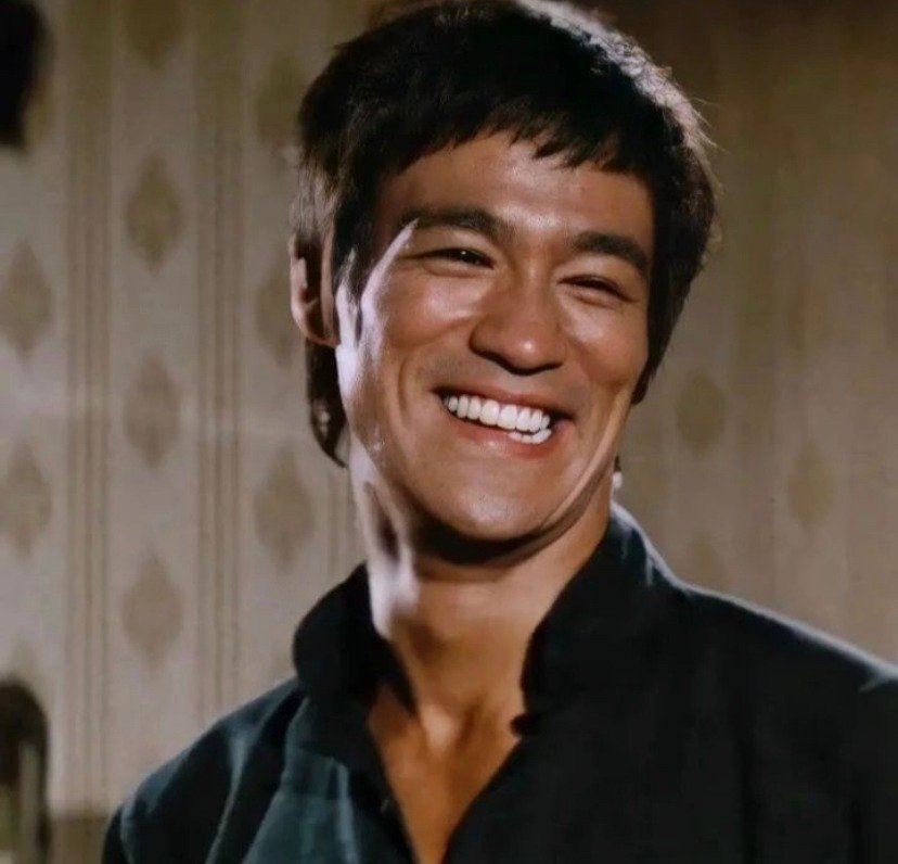 Uśmiechnięty Bruce Lee w czarnej koszuli