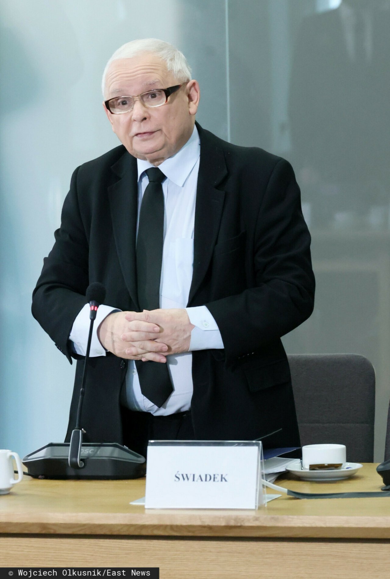 Jarosław Kaczyński w czarnym garniturze stoi przed komisją