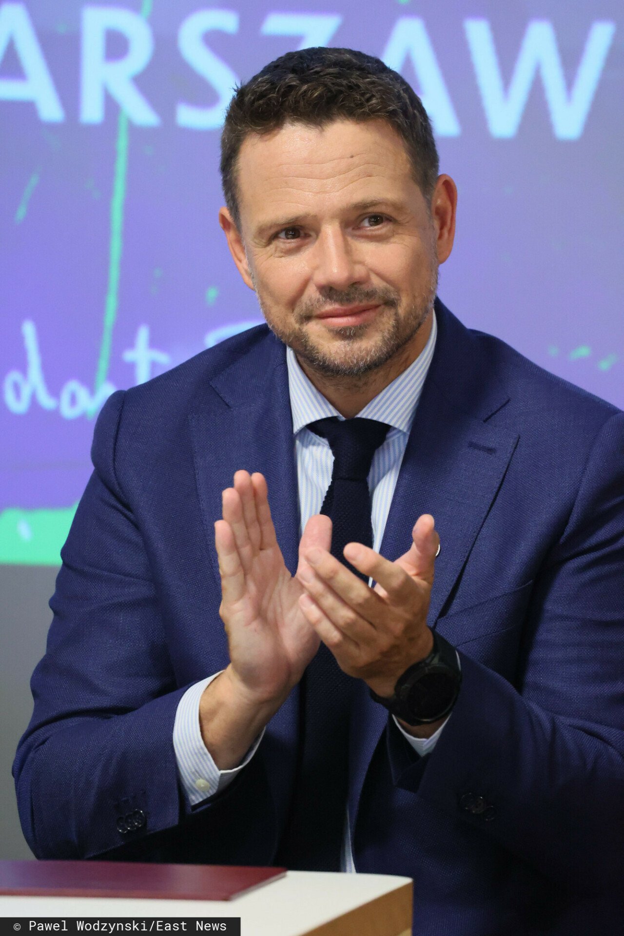 Klaszczący Rafał Trzaskowski w garniturze