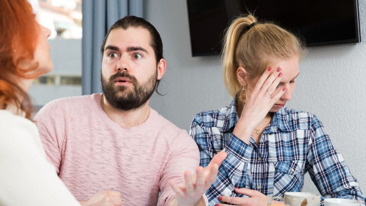 zdziwiony mężczyzna, obok niego kobieta chowa twarz w dłoni